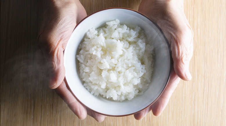 hands holding white rice bowl