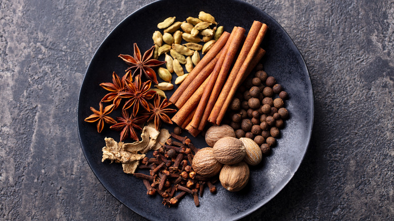 whole chai spices on black dish