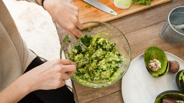 Person making guacamole on countertop