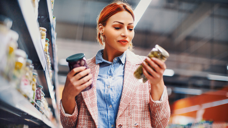 Woman choosing between olives in store