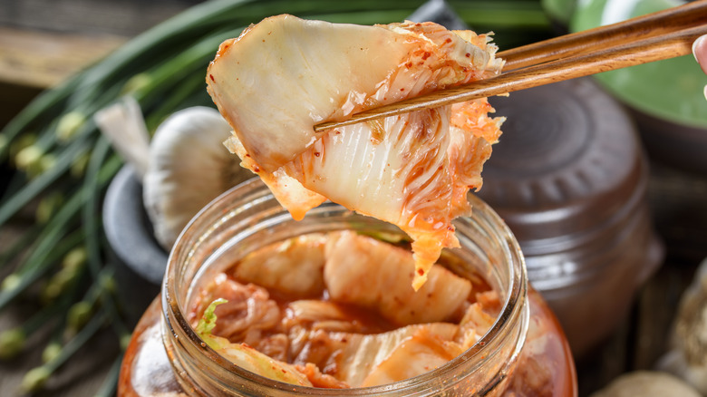 Pulling a piece of kimchi from a jar