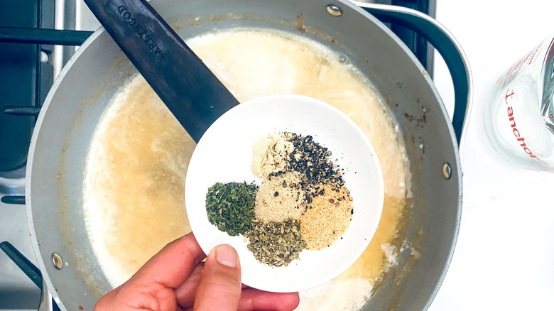 hand holding spices over pot