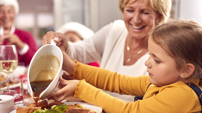 Woman serving gravy at dinner table