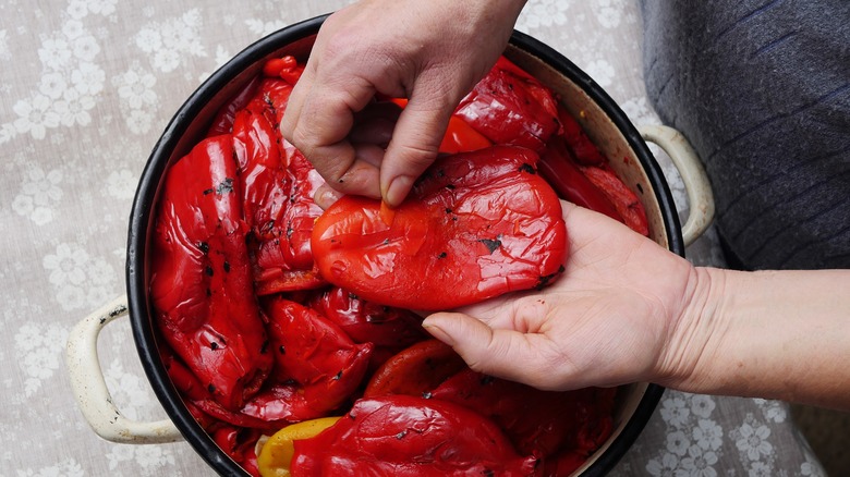 Hands peeling roasted red peppers