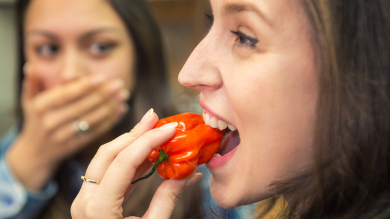 Woman biting into fresh chili pepper