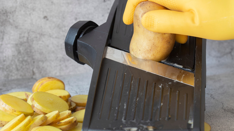 Person slicing potatoes with mandoline