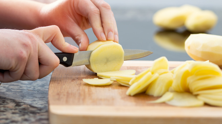 Person slicing potatoes on cutting board