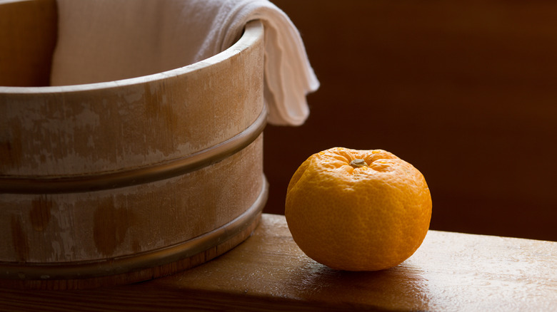 Fruit of yuzu on the edge of a wooden bath