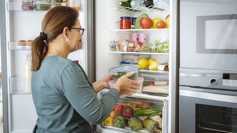 woman putting containers in fridge