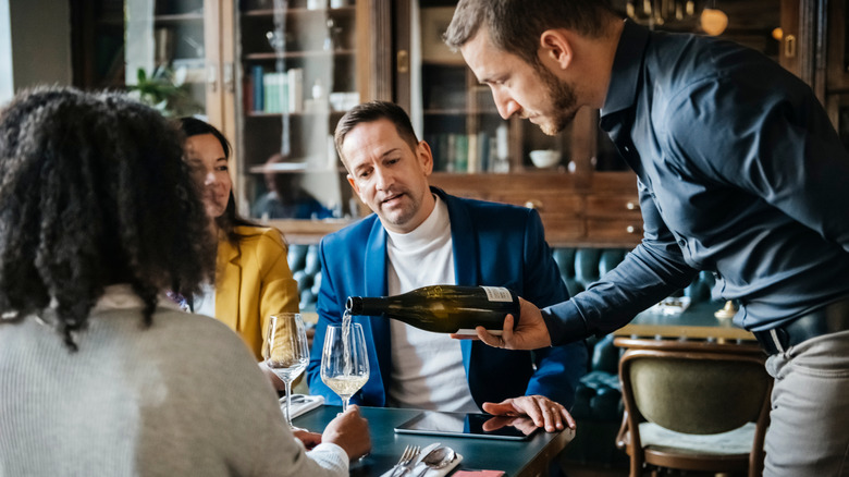 server pours wine at fancy restaurant