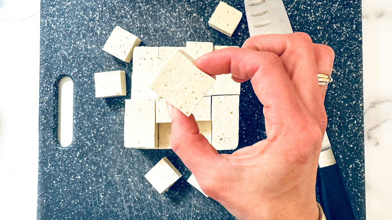 hand holding cubed tofu piece