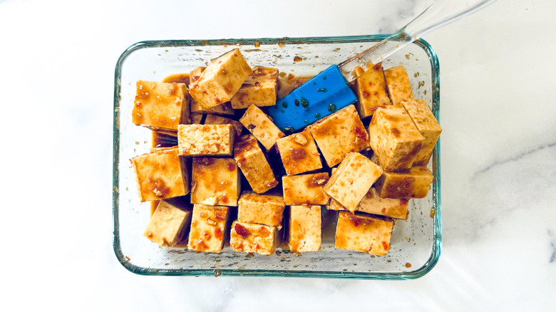 cubed tofu marinating in container