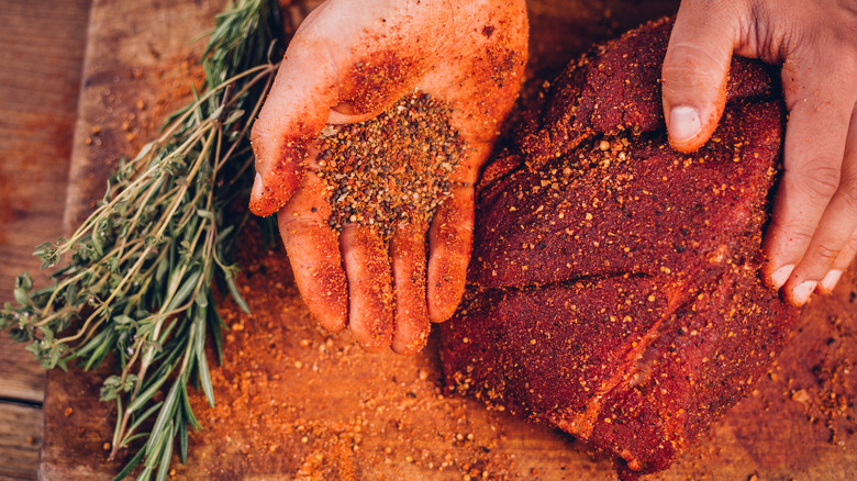 Spice rub in palm with meat and herbs