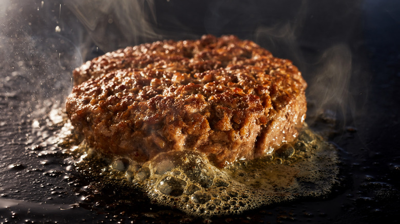 Burger patty frying on griddle