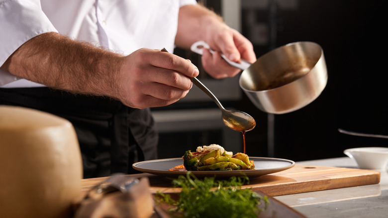 Chef pouring sauce over dish