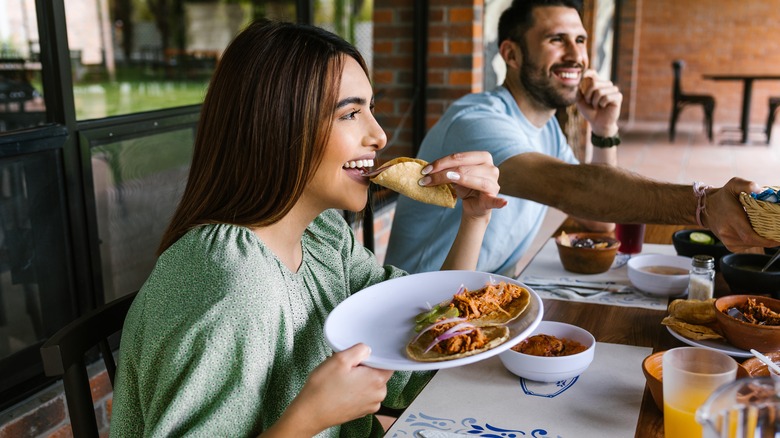 Woman eating tacos at restaurant