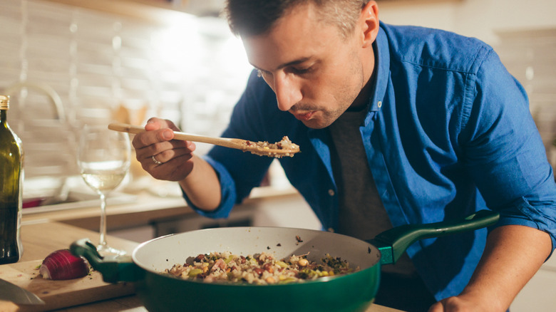 man taste testing risotto during cooking