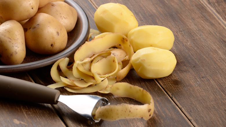 Peeled raw potatoes on a wooden table