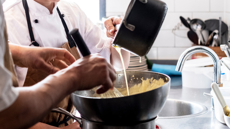 Two chefs making hollandaise 