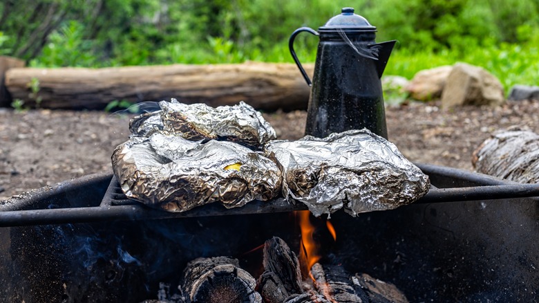Foil-wrapped potatoes over campfire