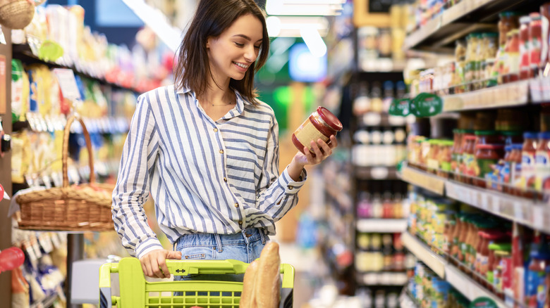 Person grocery shopping holding jar