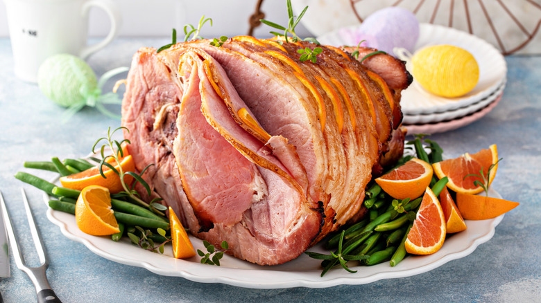 Bone-in ham sliced on a platter with garnishes