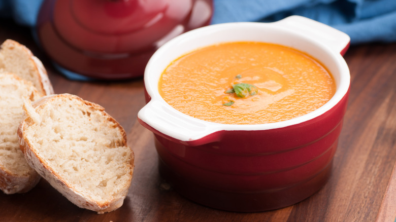 bread next to pot of tomato soup