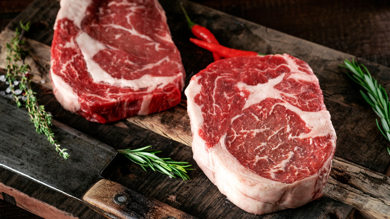 raw rib eye steaks on cutting board
