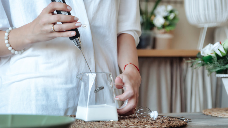 Frothing milk in glass pitcher