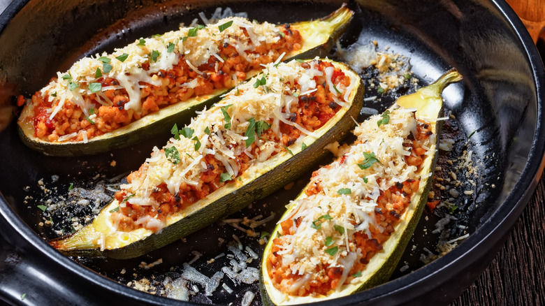 Three stuffed zucchini boats on a black skillet