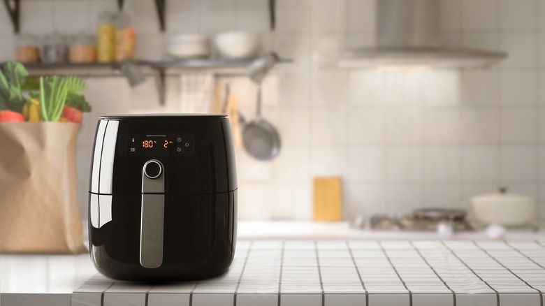 Black air fryer on a white tiled counter