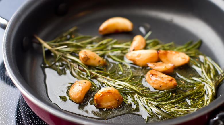 Garlic and rosemary in oil on pan