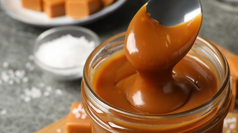 jar of caramel sauce with caramel candies in the background