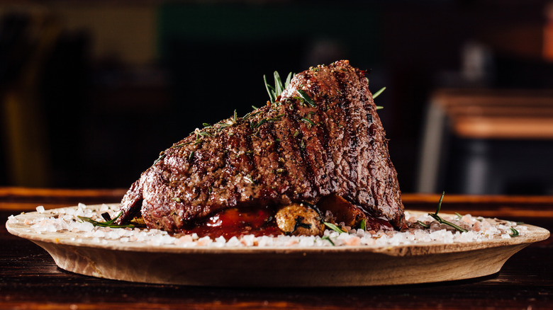 Seasoned steak on a round wooden board