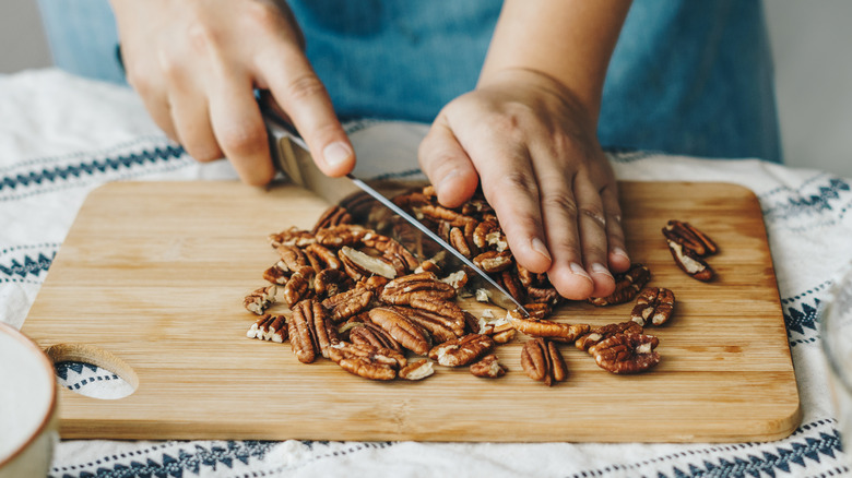 Person chopping pecans on cutting board