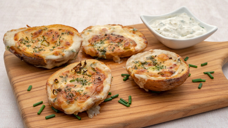 Cooked potato skins on a chopping board with dip