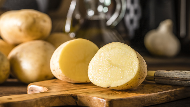 Raw potato cut in half on a board