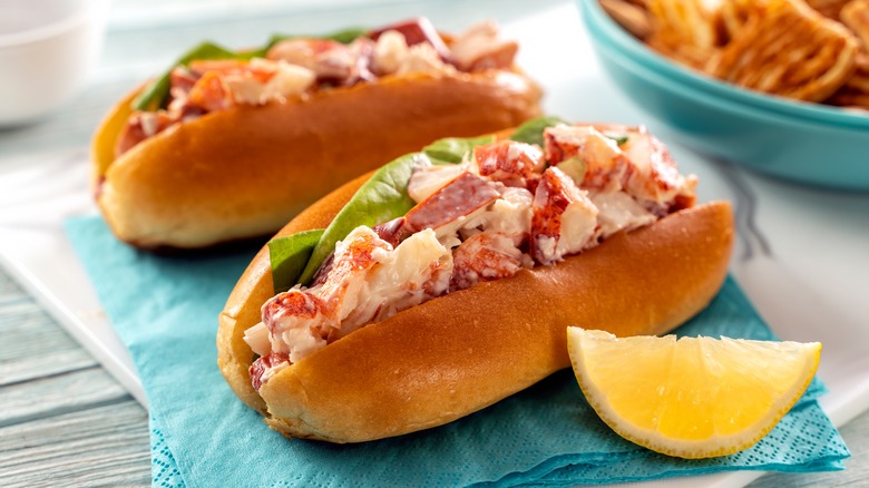 Two lobster rolls with lemon wedge