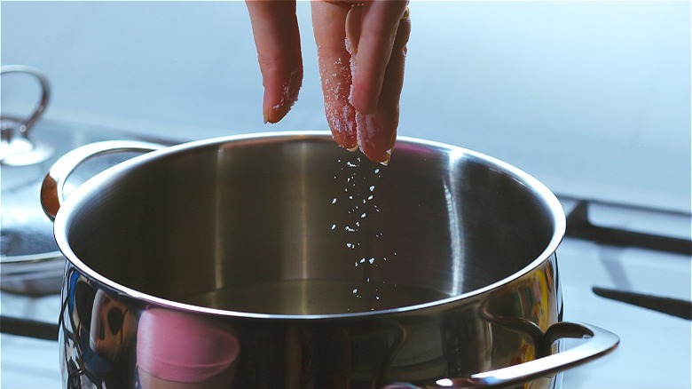 Hand with salt over pot