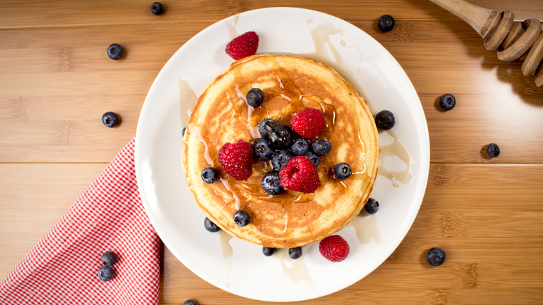 Pancakes with berries and syrup on table