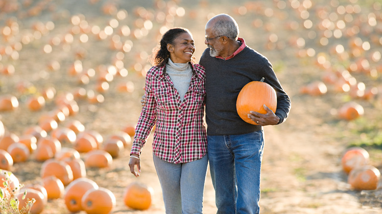 Couple carrying a pumpkin in a field