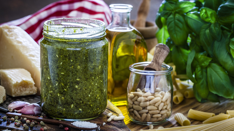 pesto, olive oil, and pine nuts in jars on table