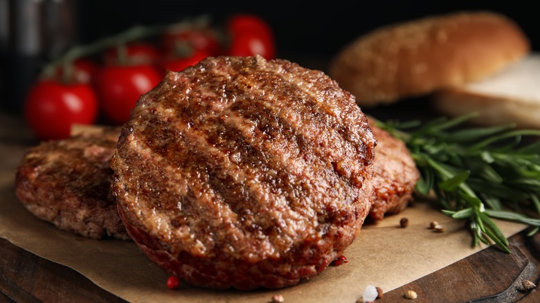 cooked burger patties on cutting board