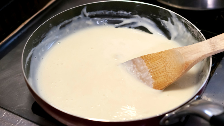 Creamy béchamel cooking in a pan on a griddle
