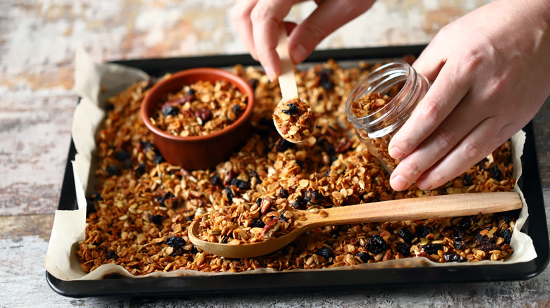 hand scooping granola from pan