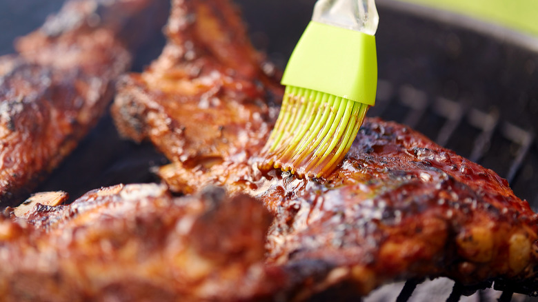 Meat being basted with silicone brush on grill