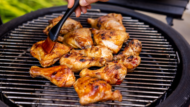 Grilled chicken being basted with a brush