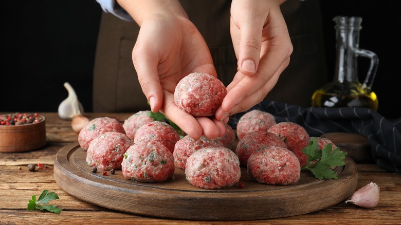 arranging batch of uncooked meatballs