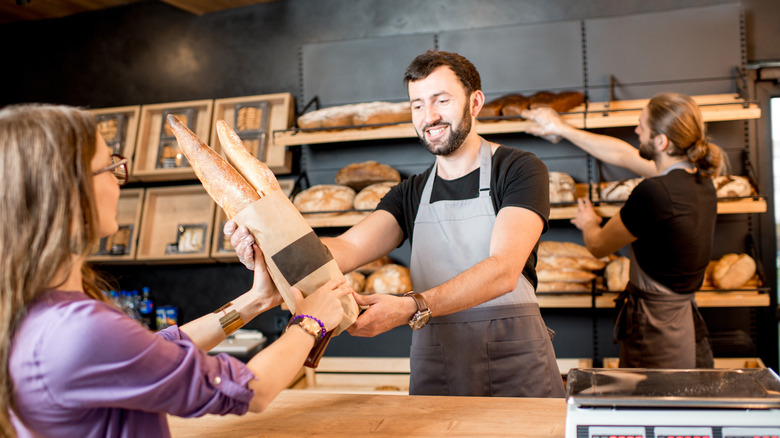 shopper buying baguette at store