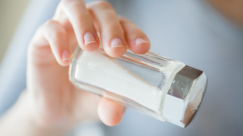 hand holding salt shaker